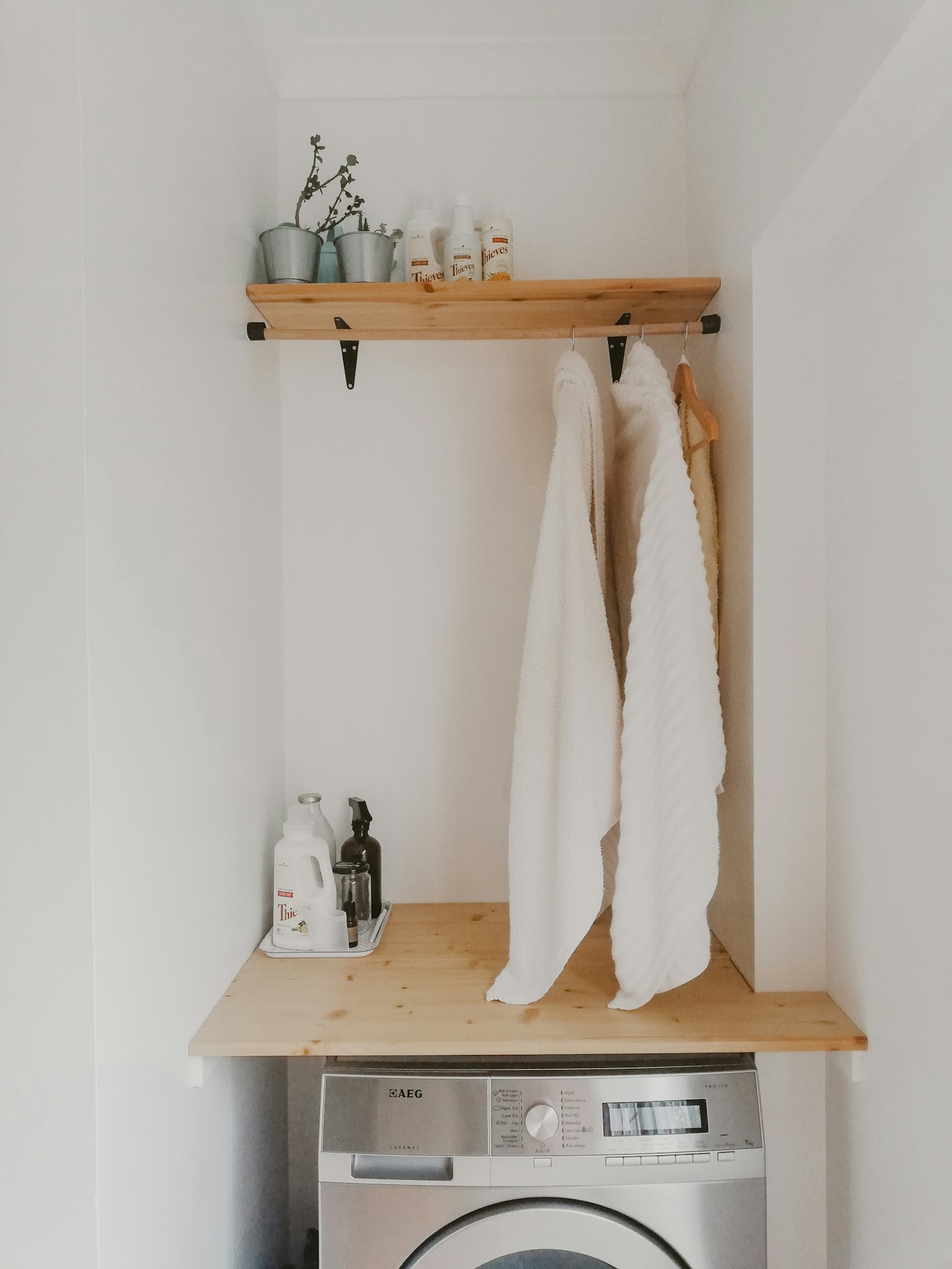 Light-colored towels hanging from hooks above a small bathroom cabinet.