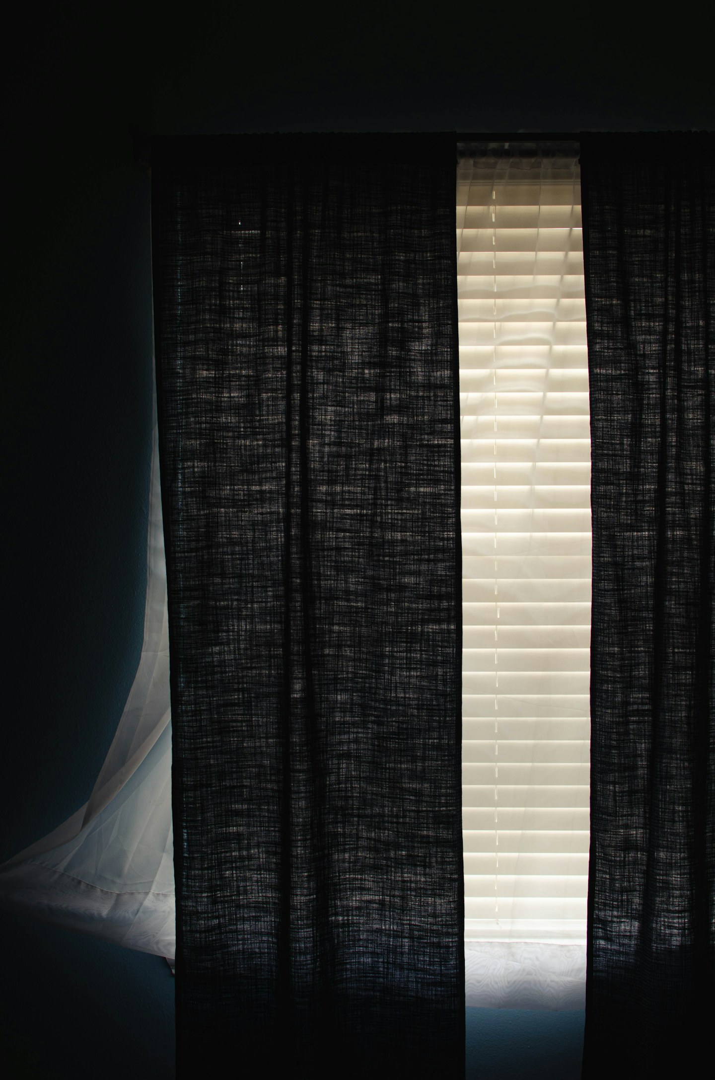 Dark curtains framing a narrow strip of daylight at a window.