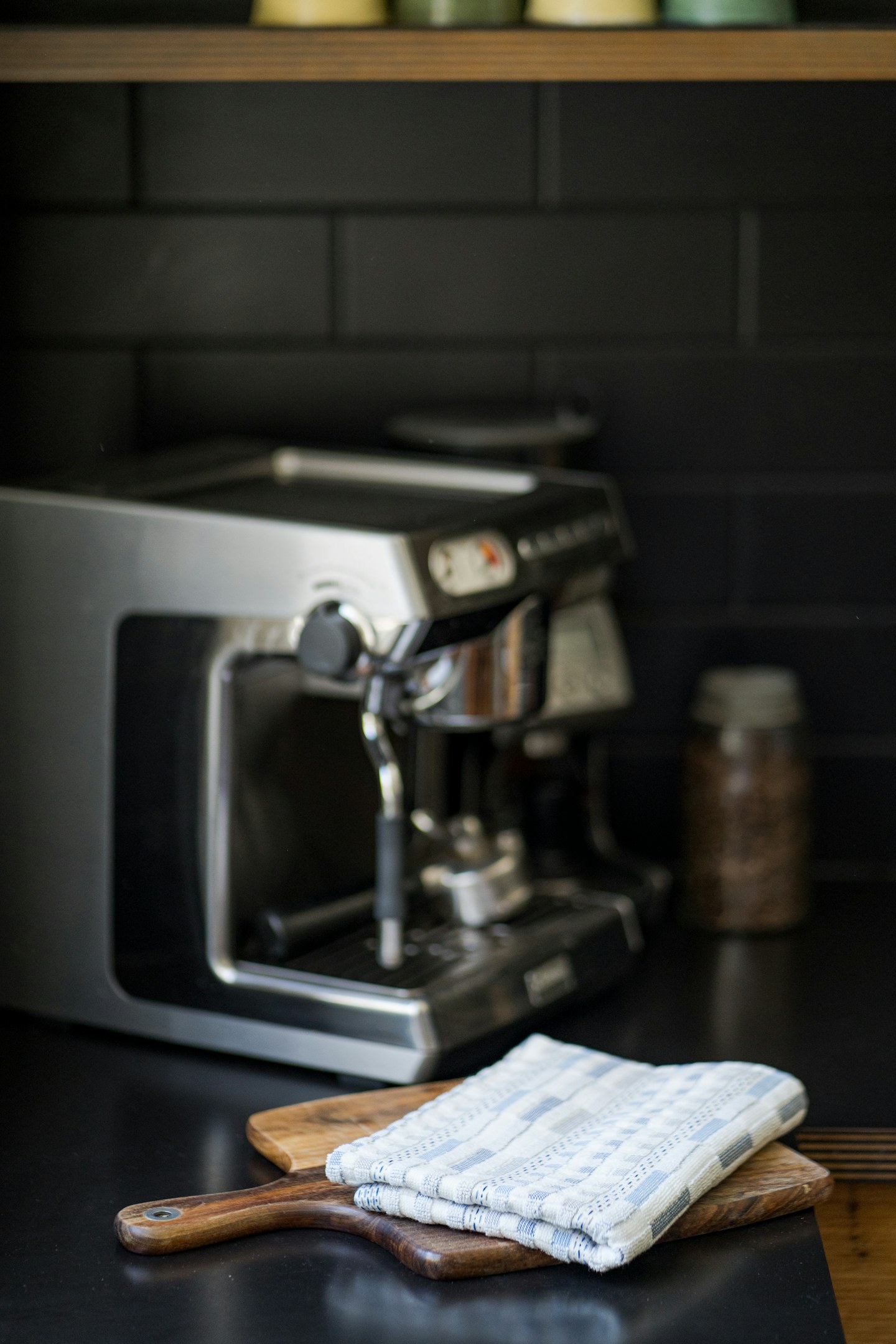 A countertop coffee station with a coffee maker, cloth, and wooden utensils.