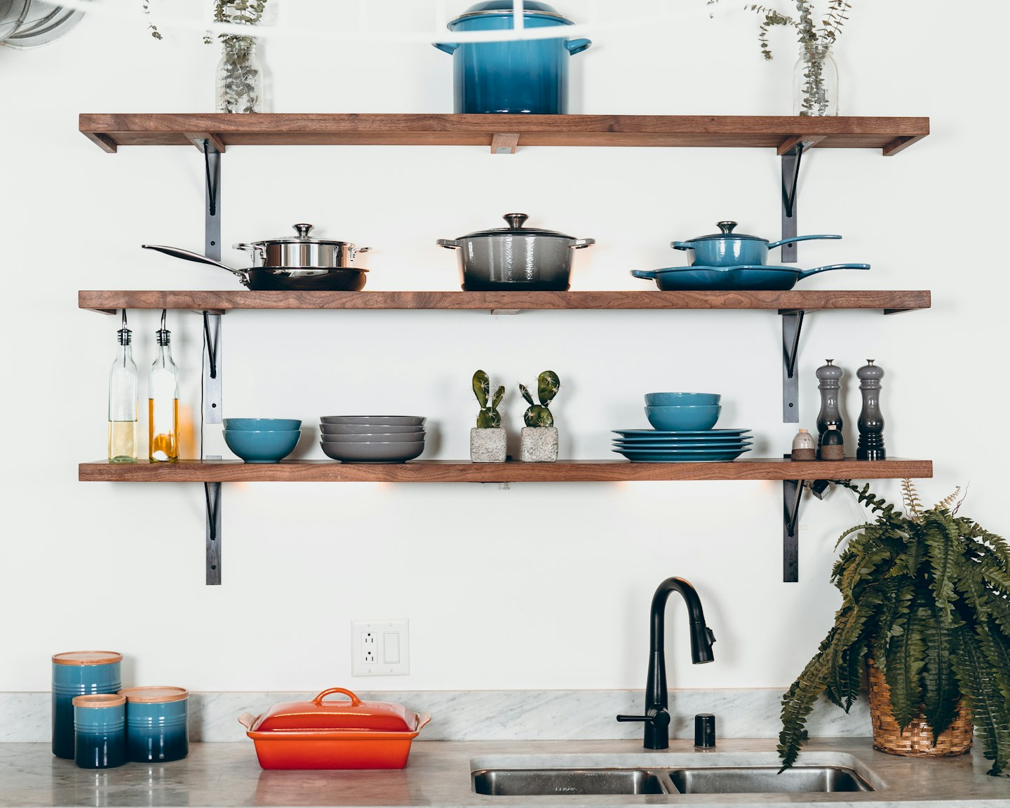 Open kitchen shelves holding cookware, bowls, and cooking utensils.