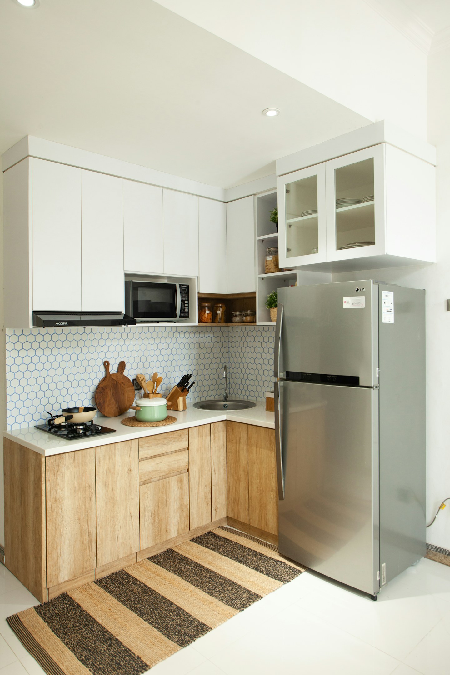 A compact kitchen with a refrigerator, stove, and wooden cabinets.