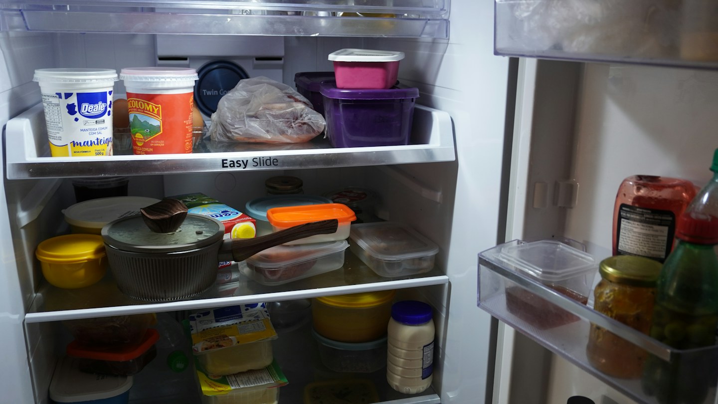 An open refrigerator containing food containers, jars, and a covered pan.