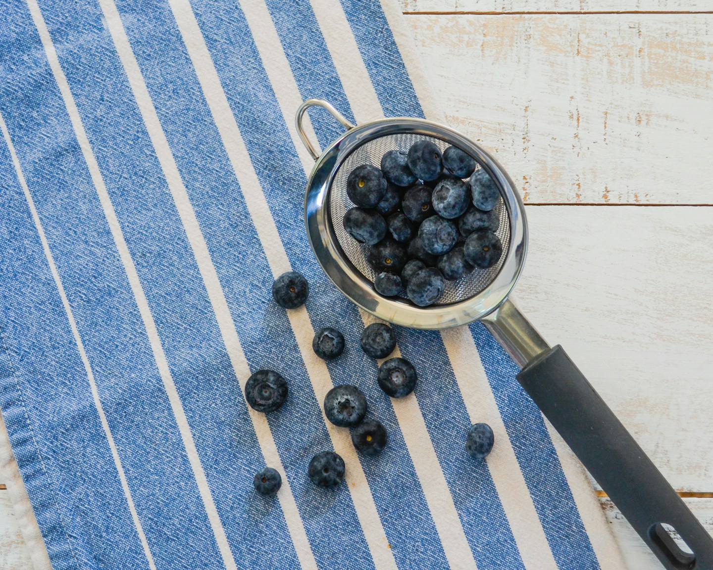 A bowl of blueberries on a blue striped kitchen towel.