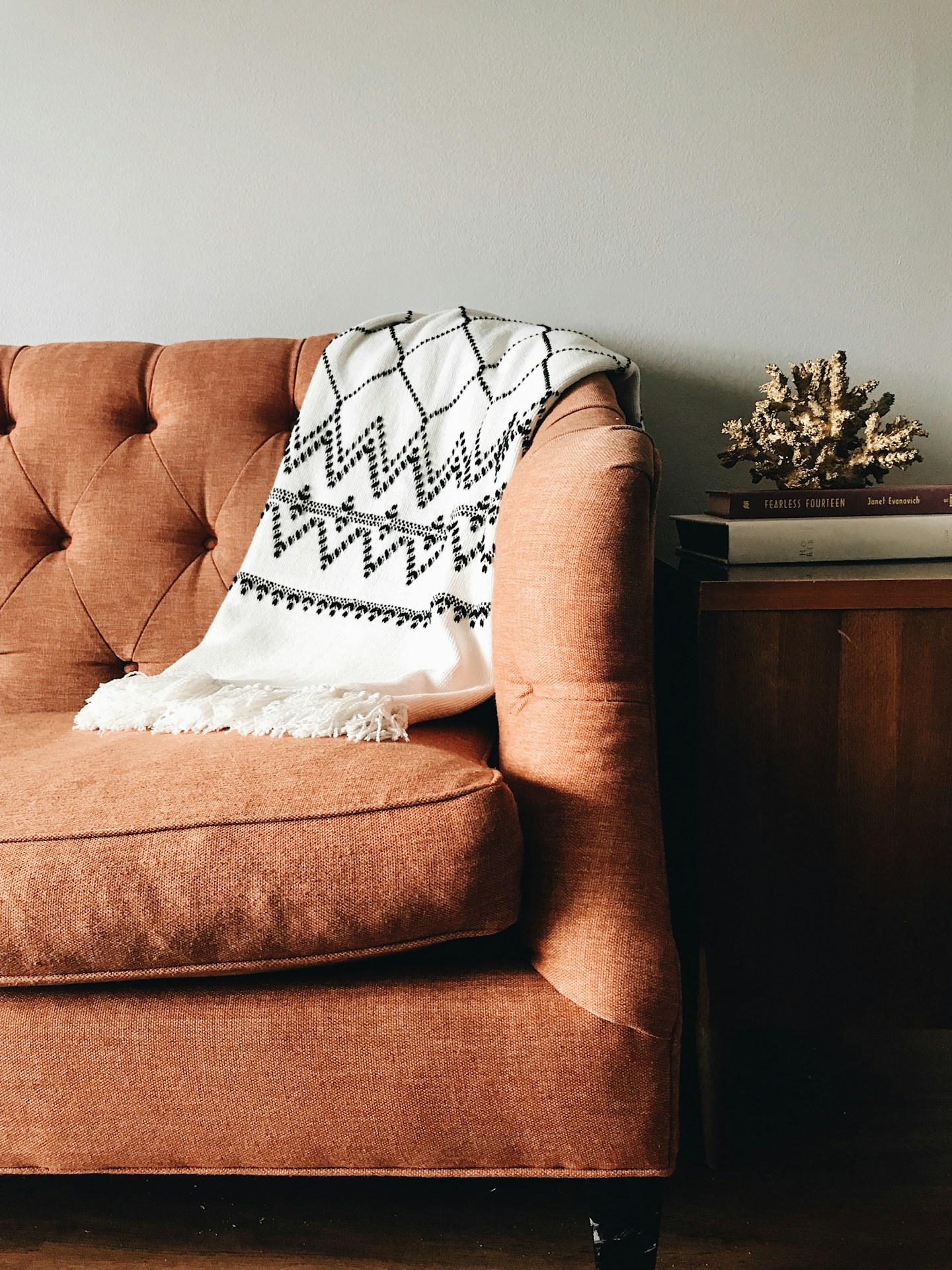 A patterned throw blanket draped over a tufted sofa.