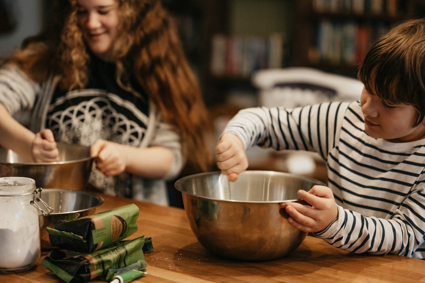 Two people preparing food together with a metal mixing bowl at a counter.