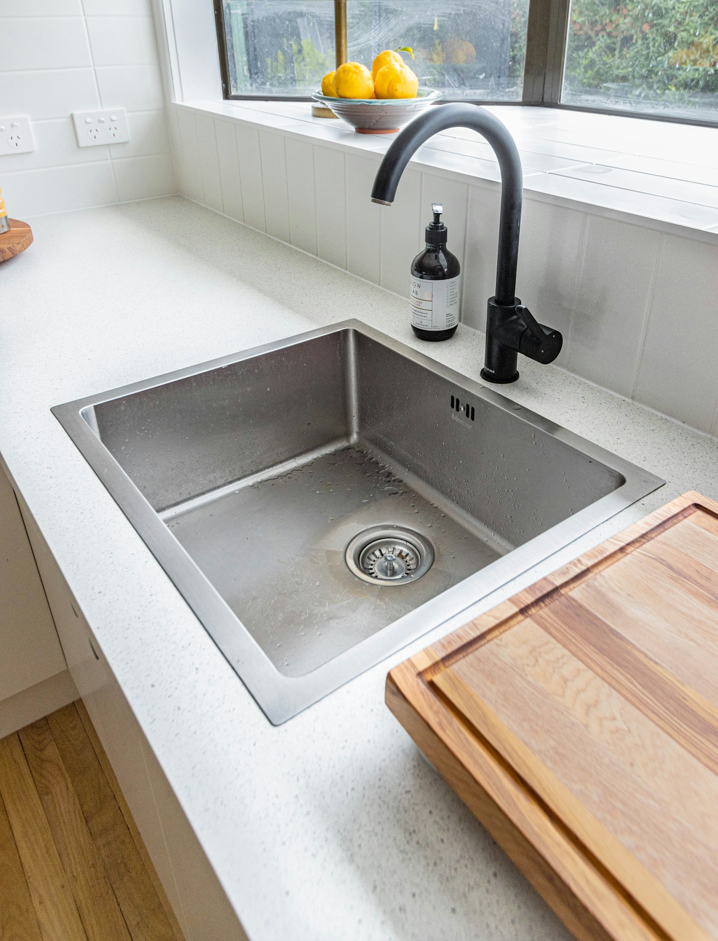 A kitchen sink with a dark faucet beside a wooden countertop.